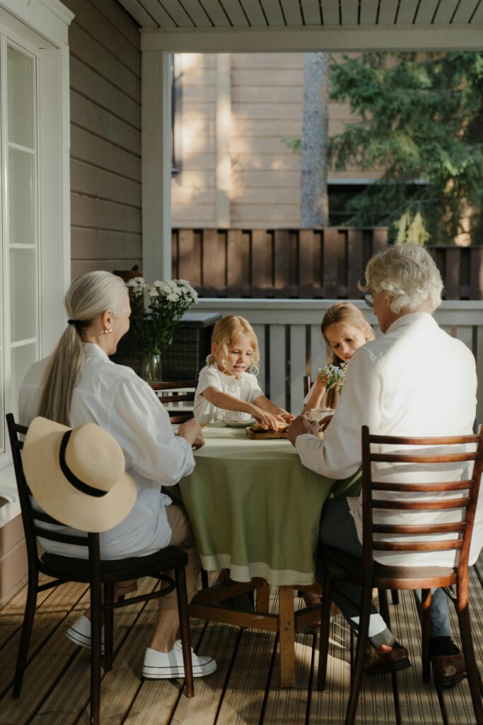 Grandparents and grandchildren enjoying quality time on a cozy porch.