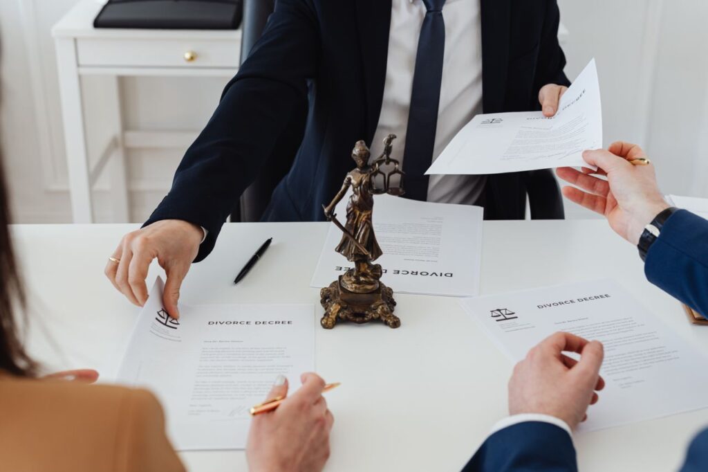 pexels-photo-7876051-7876051 Three adults discussing divorce documents in a formal office setting with legal statue in view.